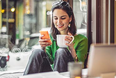 a woman in a coffee shop looking at her phone.