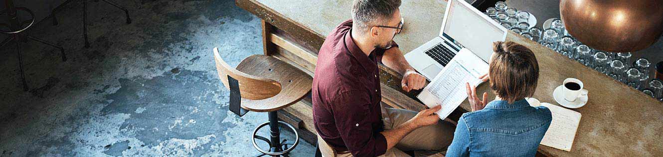 A couple sitting at a table in front of a laptop.